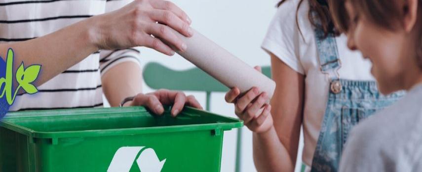 3 children help a parent to sort paper towel rolls into a recycling bin.